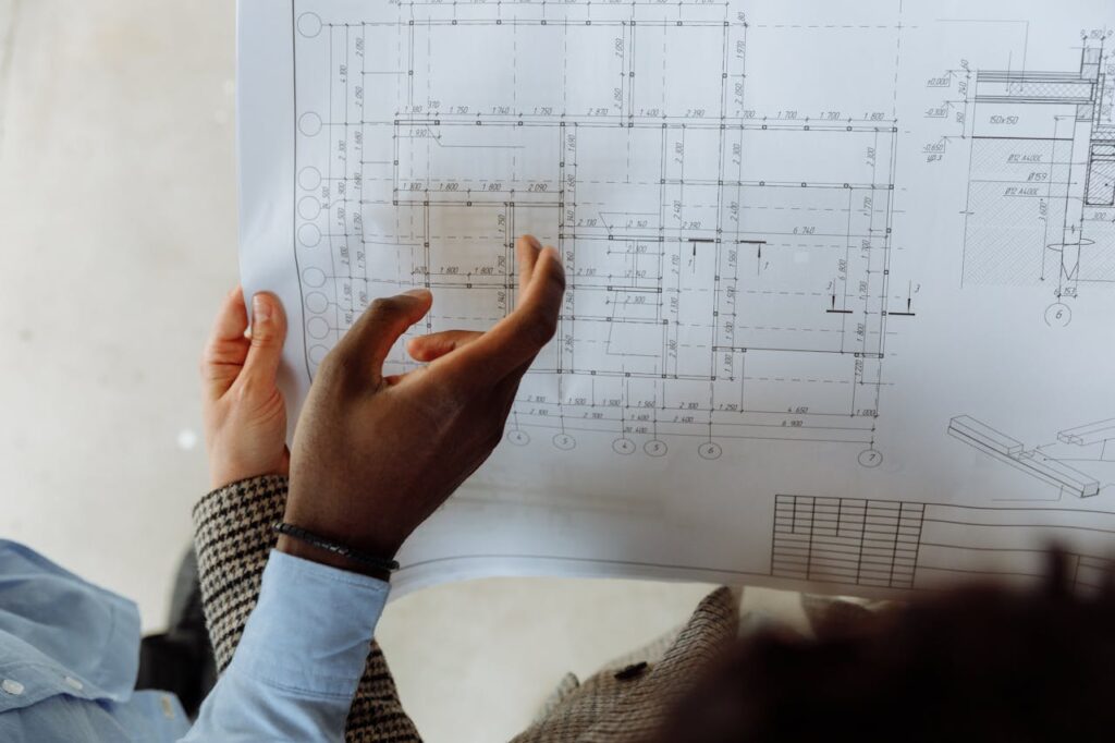 In-depth view of hands examining a detailed architectural blueprint with precise measurements.